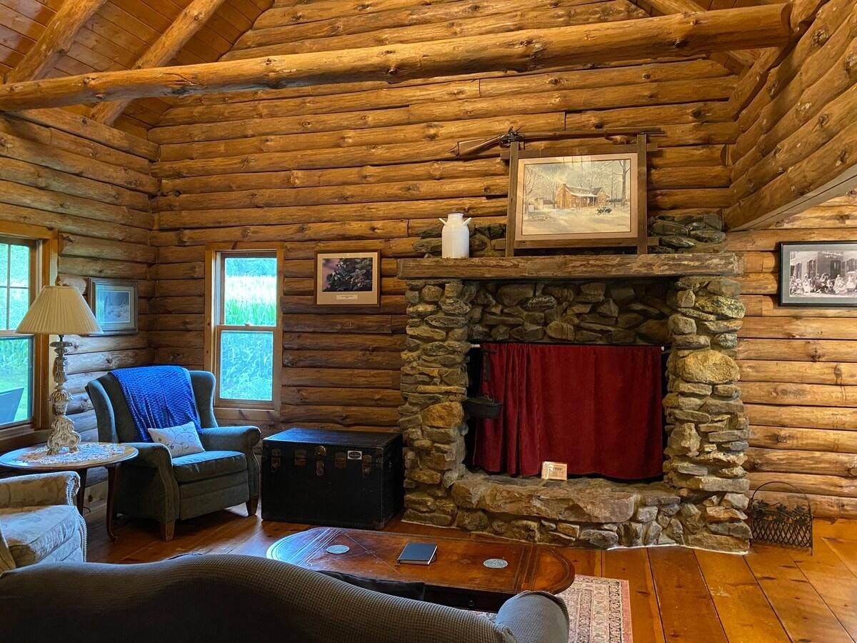 Cabin grand sitting room has great light, an impressive custom stone fireplace, vaulted ceiling with a magnificent chandelier next to the dining area that seats 6. These logs provide peace and comfort - it truly is a great place to sit!
